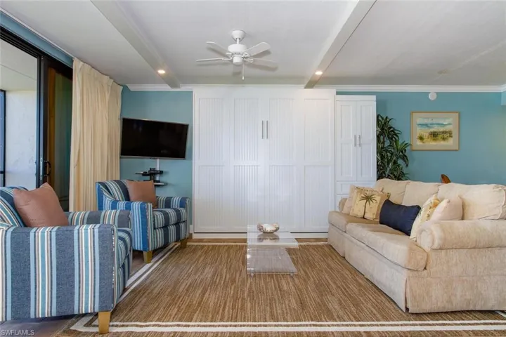 Living room with ceiling fan and ornamental molding