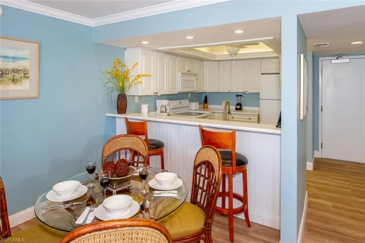 Kitchen with white appliances, a breakfast bar area, and light hardwood / wood-style flooring