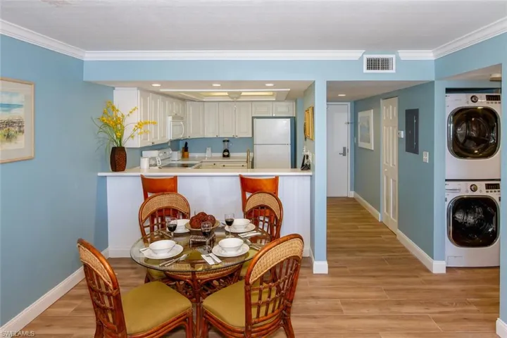 Dining room featuring stacked washer and clothes dryer, ornamental molding, and light hardwood / wood-style flooring