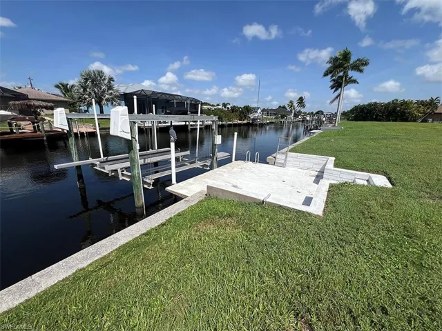 View of dock with a water view and a lawn