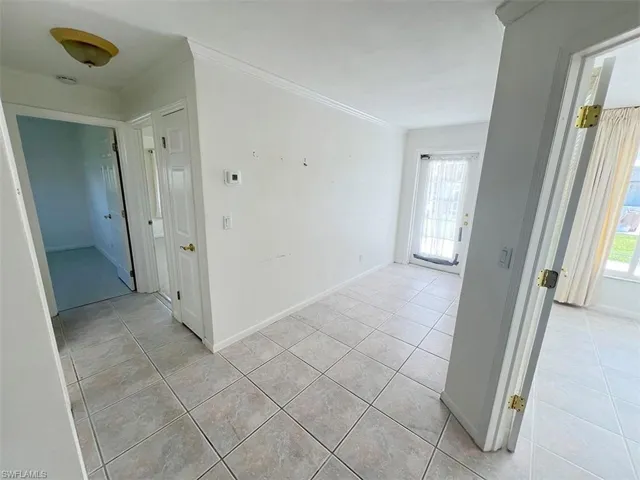 Hall with light tile patterned floors and crown molding