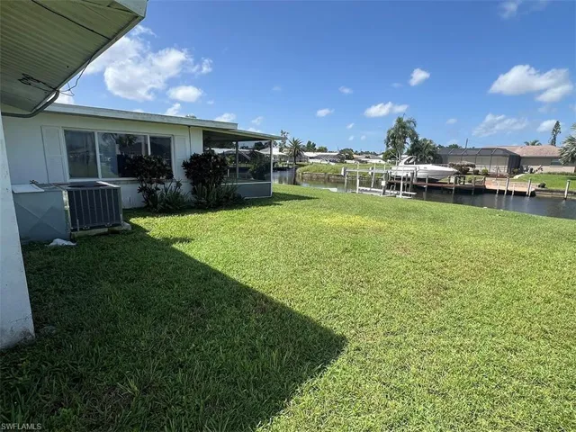 View of yard with a water view, a dock, and central air condition unit