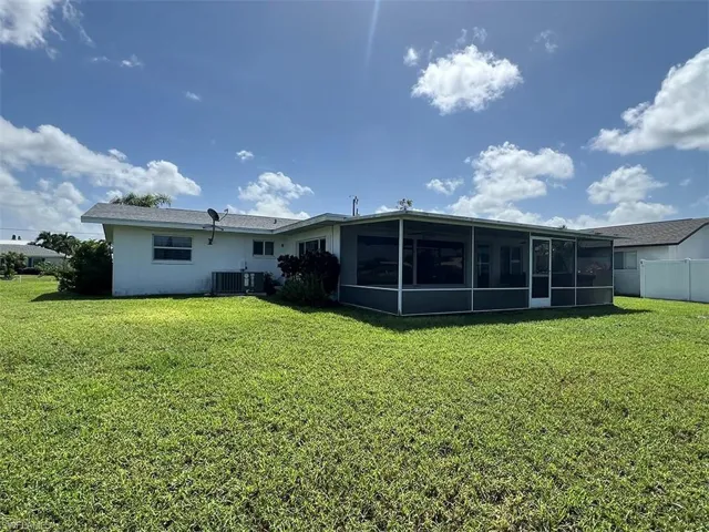 Rear view of house featuring a yard, cooling unit, and a sunroom