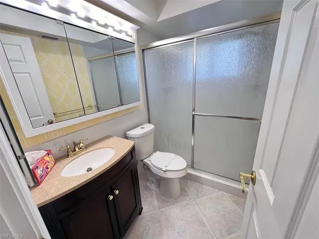 Bathroom featuring tile patterned flooring, vanity, toilet, and an enclosed shower