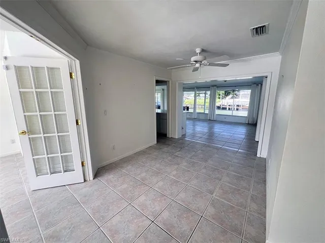 Tiled empty room with crown molding and ceiling fan