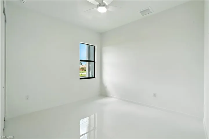 Tiled spare room with ceiling fan and baseboards