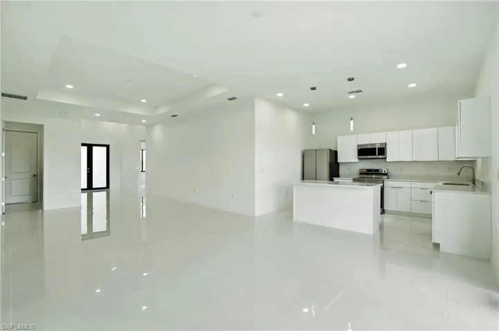 Kitchen with open floor plan, white cabinetry, light tile patterned floors, recessed lighting, and a center island