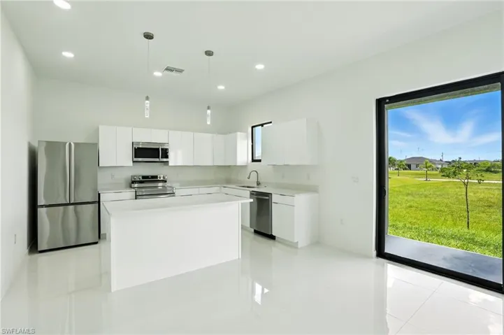Kitchen with stainless steel appliances, white cabinets, decorative light fixtures, a kitchen island, and modern cabinets