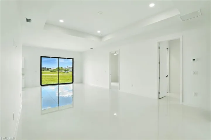 Empty room featuring a raised ceiling, recessed lighting, and light tile patterned floors