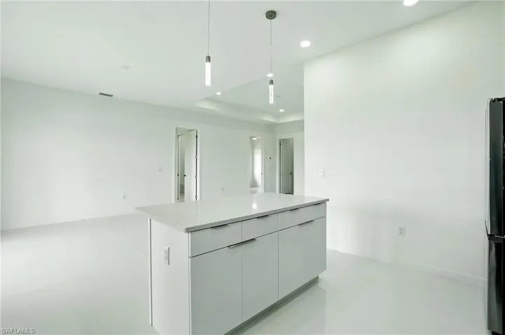 Kitchen featuring modern cabinets, pendant lighting, white cabinets, recessed lighting, and a kitchen island