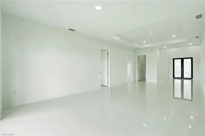 Empty room featuring light tile patterned floors, recessed lighting, and a raised ceiling