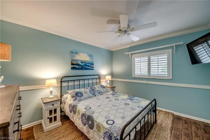 Bedroom featuring ornamental molding, wood finished floors, and a ceiling fan