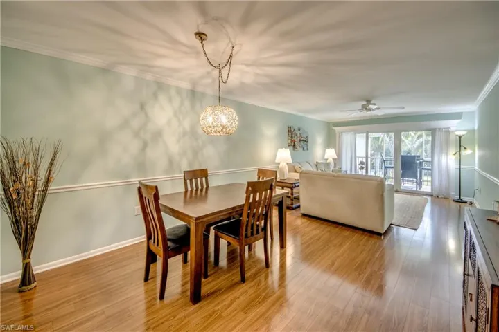 Dining room featuring ceiling fan, light wood-type flooring, crown molding, and a chandelier