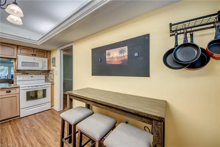 Kitchen featuring white appliances, light wood-style flooring, and light stone counters