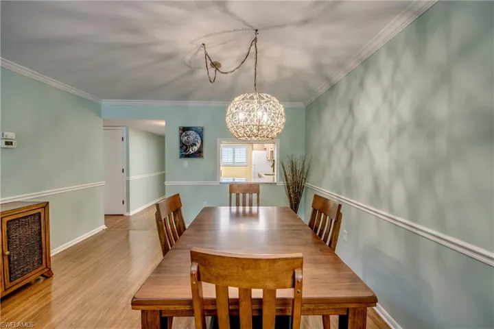 Dining space featuring wood finished floors, suspended lighting, and ornamental molding