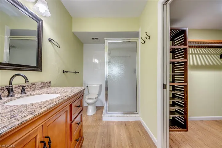 Full bathroom featuring vanity, a walk in closet, a stall shower, light wood-style flooring, and wine cooler