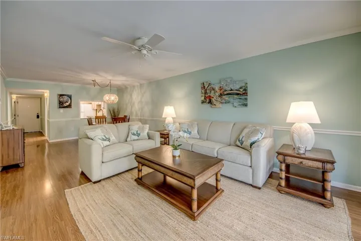 Living area with crown molding, a ceiling fan, and wood finished floors