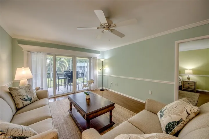 Living room with wood finished floors, crown molding, and ceiling fan