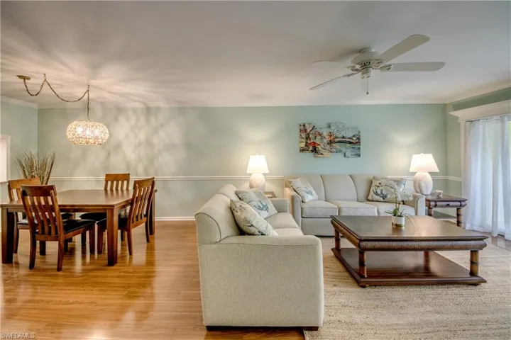 Living area featuring ornamental molding, light wood-style flooring, ceiling fan, and hanging lights