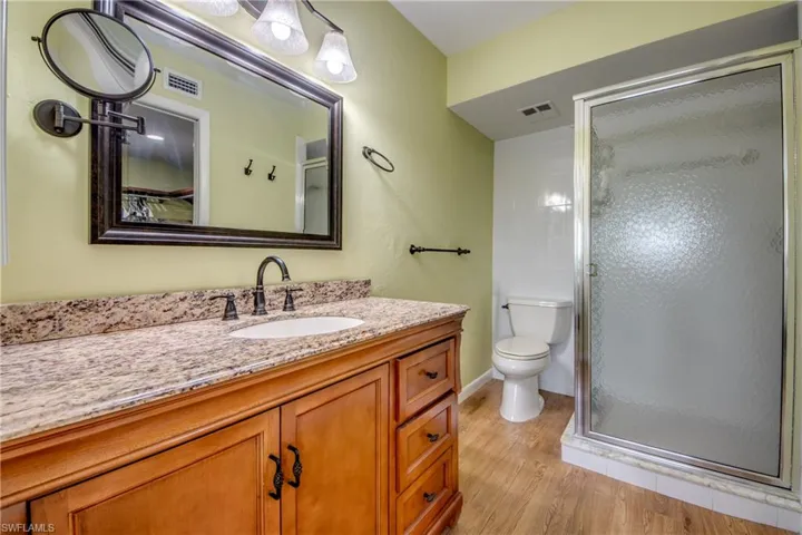 Full bath with vanity, a stall shower, and light wood-type flooring