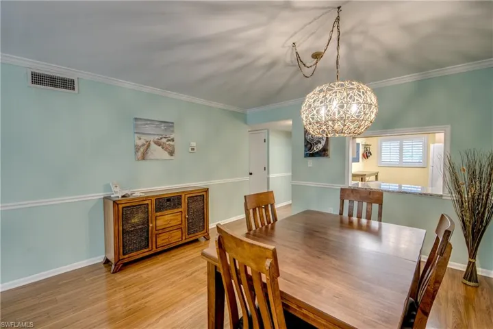 Dining area with wood finished floors, crown molding, and hanging lights