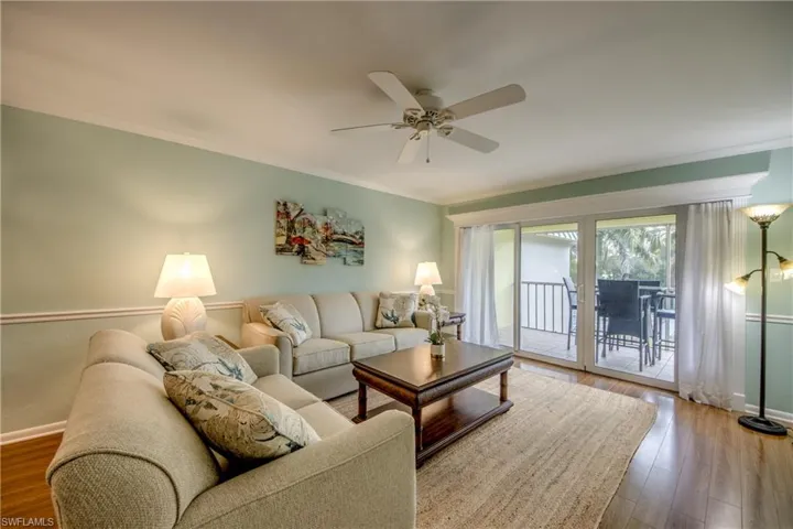 Living area with wood-type flooring, ornamental molding, and a ceiling fan