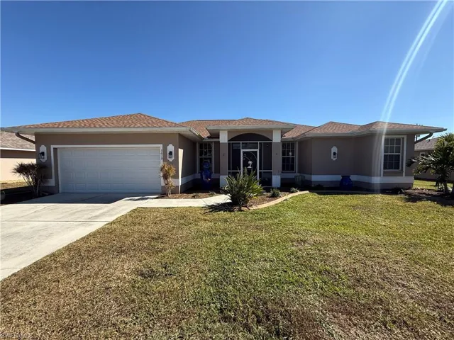 Ranch-style home featuring stucco siding, a front lawn, driveway, and an attached garage
