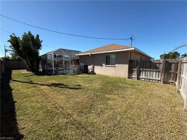 Fenced backyard with a lanai and a sunroom