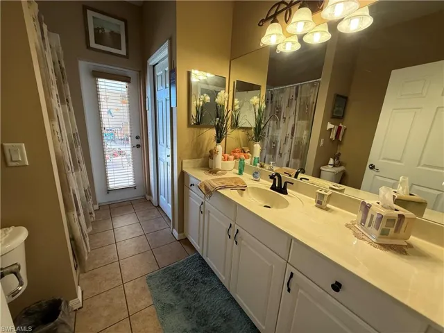 Bathroom with vanity, curtained shower, and light tile patterned flooring