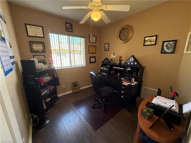 Office with dark wood-style flooring and ceiling fan