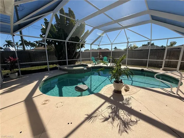 Combined pool / hot tub featuring a lanai, a patio area, a fenced backyard, and a sunroom