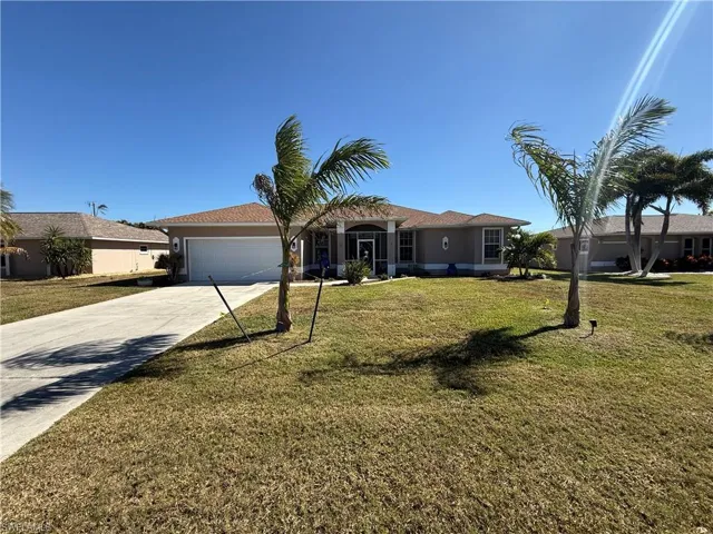 Ranch-style home featuring concrete driveway, stucco siding, a front yard, and a garage