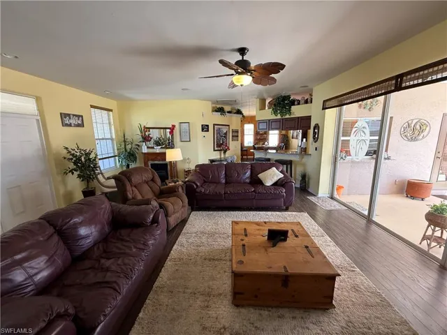 Living area featuring ceiling fan, healthy amount of natural light, hardwood / wood-style floors, and a fireplace