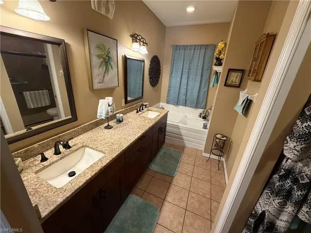 Full bathroom featuring double vanity, light tile patterned flooring, a bath, and a shower