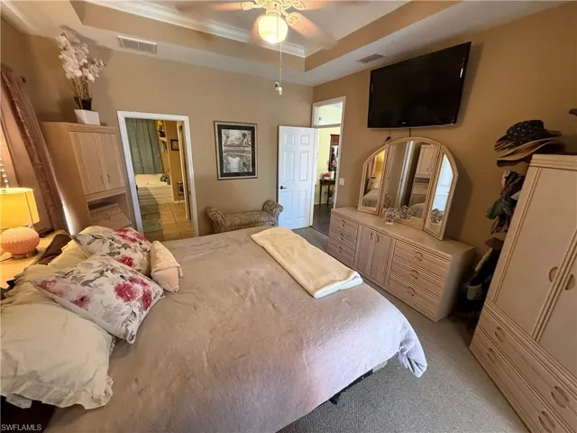 Bedroom featuring crown molding, ceiling fan, a closet, light colored carpet, and a raised ceiling