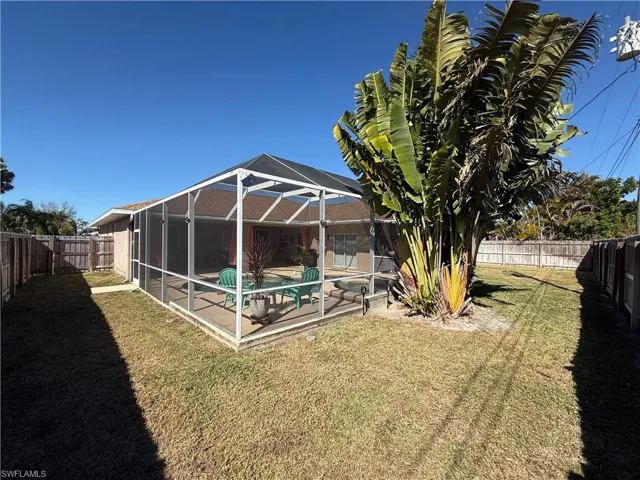 Fenced backyard featuring glass enclosure, a sunroom, and a patio area
