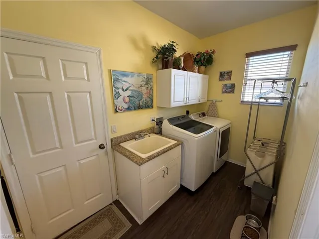 Laundry area featuring cabinet space, dark wood finished floors, and washer and dryer