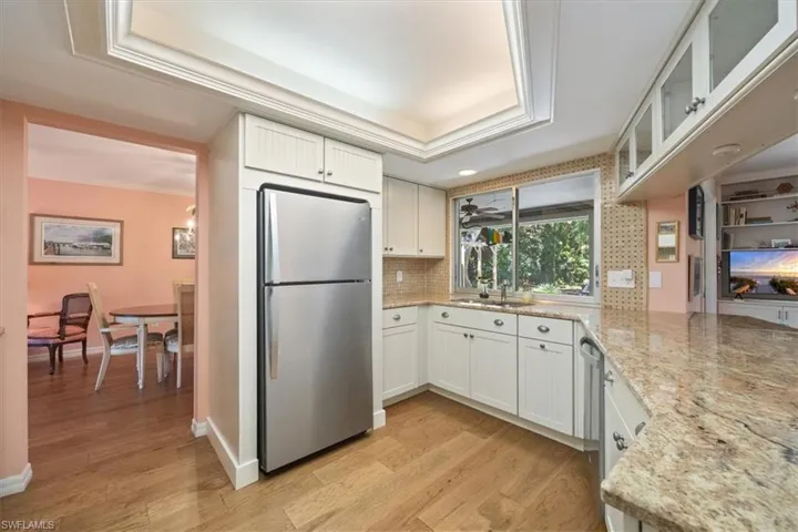 Kitchen with light wood-style flooring, a raised ceiling, freestanding refrigerator, and ornamental molding