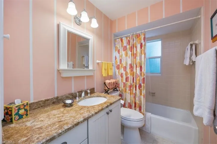 Full bathroom with tile patterned floors, toilet, vanity, and shower / bath combination with curtain