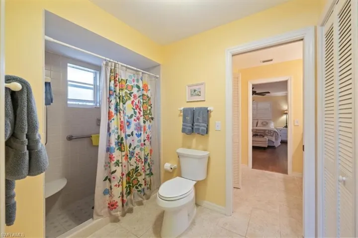 Full bath with tile patterned floors, toilet, a closet, and a stall shower