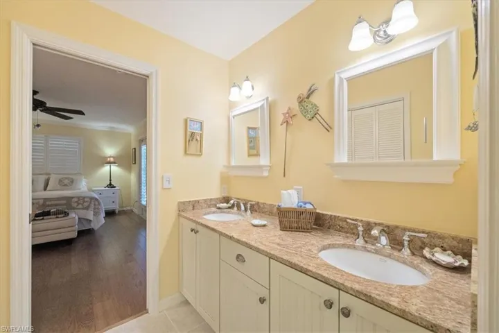 Full bathroom featuring double vanity, ensuite bath, a ceiling fan, and a sink