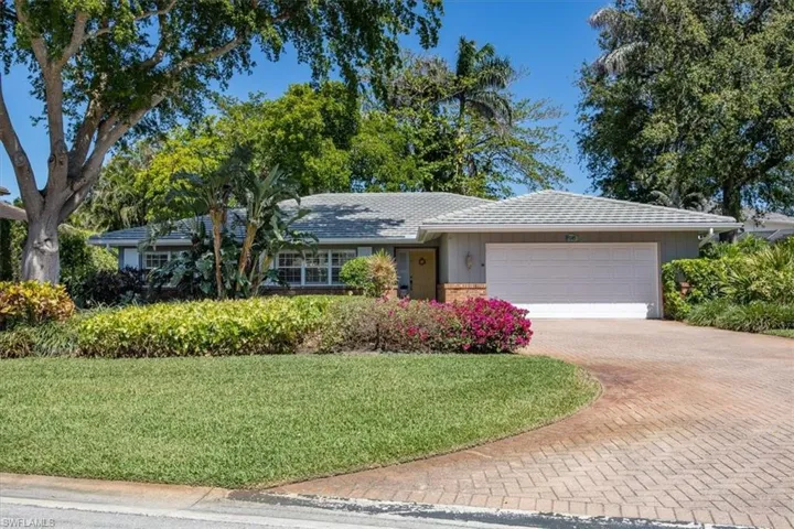Ranch-style home featuring brick siding, a front yard, decorative driveway, and a garage