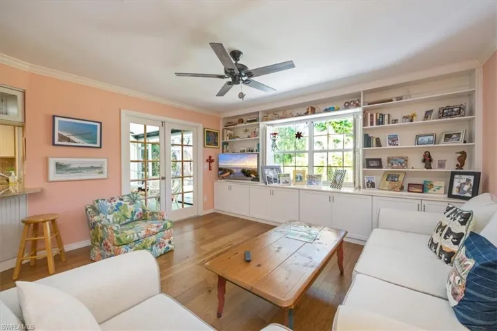Living area featuring a ceiling fan, crown molding, wood finished floors, and baseboards