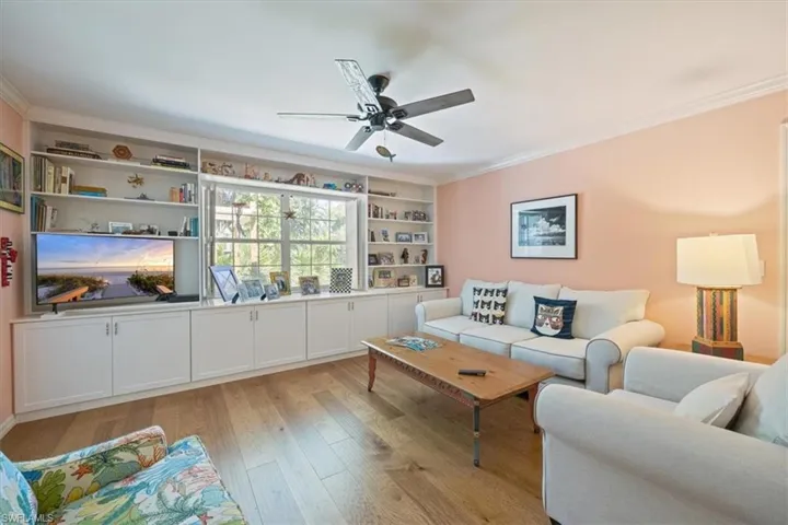Living area with crown molding, light wood-style floors, and a ceiling fan