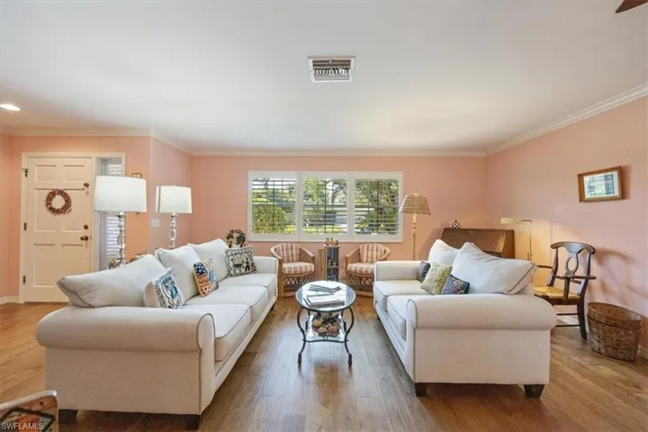 Living area with visible vents, ornamental molding, and wood finished floors