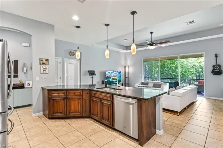 Kitchen with light tile patterned flooring, sink, decorative light fixtures, ceiling fan, and stainless steel appliances