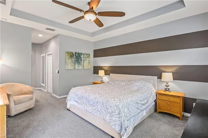 Bedroom with ceiling fan, a raised ceiling, carpet floors, and a closet