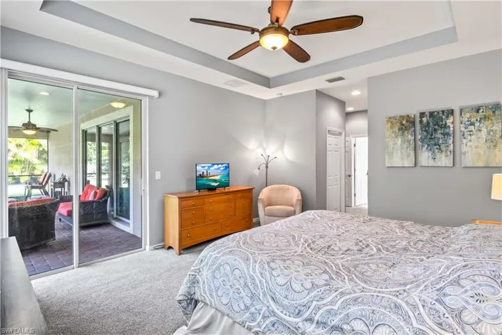 Bedroom featuring ceiling fan, a tray ceiling, carpet floors, and access to exterior