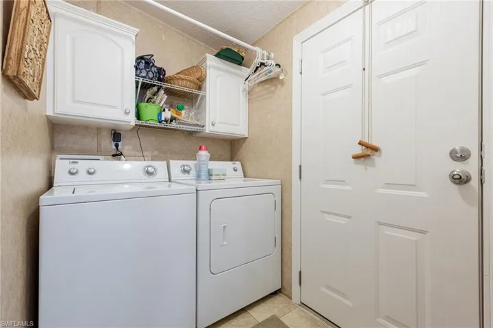Laundry room featuring washing machine and clothes dryer, a textured ceiling, and cabinet space