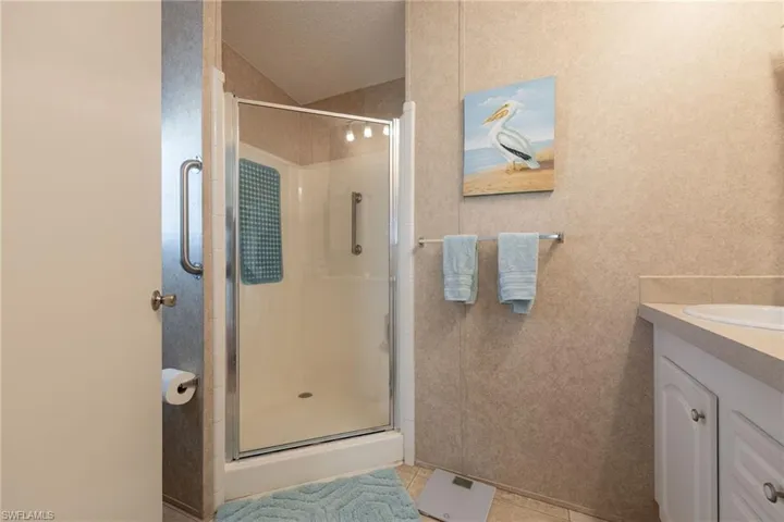 Full bathroom featuring vanity, a shower stall, a textured ceiling, and light tile patterned floors